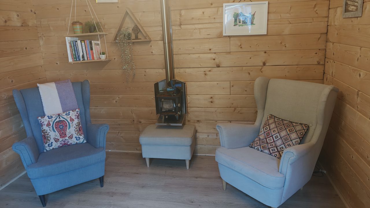 Two armchairs facing each other beside a wood stove in the counselling room